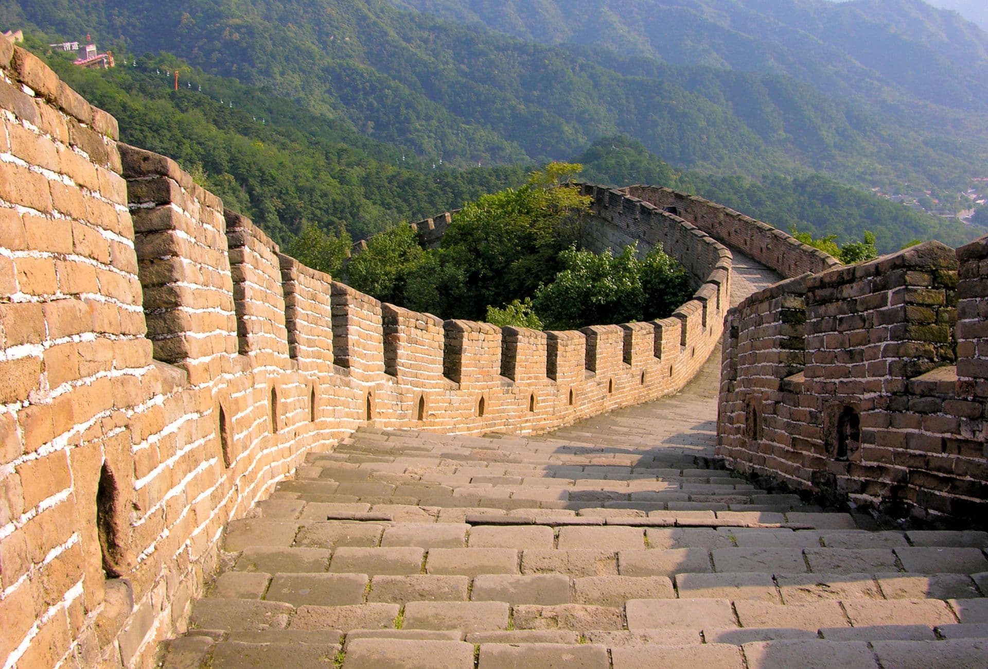 The Great Wall of China winding through forested mountains